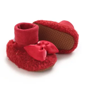 Close-up of cute red fleece baby walking shoes with a large satin bow and non-slip sole