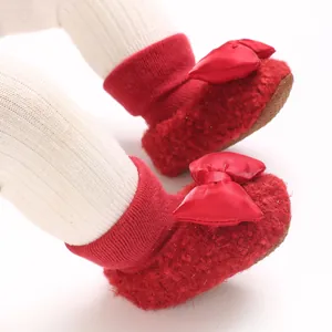 Detailed view of red plush baby walking socks with elegant satin bow and rubber sole