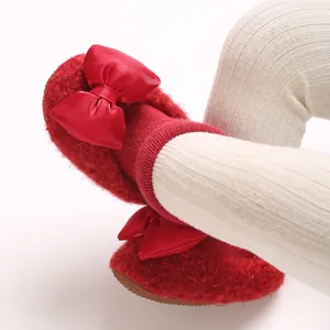 Close-up of red fleece baby walking shoes with a satin bow and thick warm lining