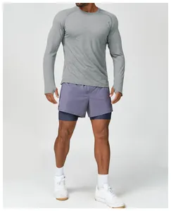 Ganzkörperaufnahme eines Mannes in grauem langärmeligem Sportshirt und lila kurzen Hosen