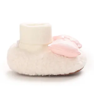 Side view of a white fluffy baby bootie featuring a soft pink satin bow detail.
