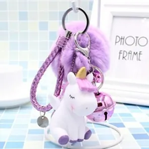 Close-up detail of a soft purple pom pom keychain with a cute white unicorn and bell