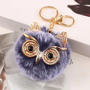 Detailed macro view of a purple owl faux fur pompom keychain with gold glitter ears