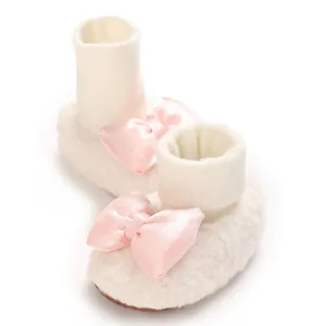 Ultra-soft cream baby booties featuring a delicate pink satin bow for newborn girls