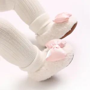 Detailed close-up view of white plush baby walker shoes with a soft pink satin bow