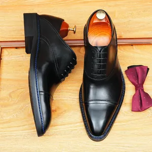 Chaussures Oxford classiques en cuir noir avec bout rapporté sur un fond de bois clair