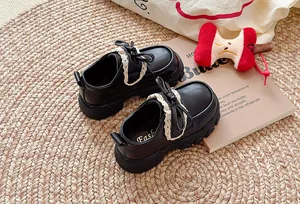 Detailansicht schwarzer Mädchen-Lederschuhe mit weißer Spitzenrüsche und Schleife