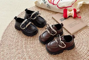 Detailansicht britischer Mädchen-Lederschuhe mit Spitzenbesatz und Schleife in Schwarz und Braun