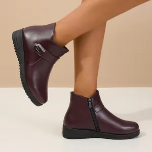 Vista detallada de botines burdeos para mujer con cremallera lateral y hebilla decorativa.