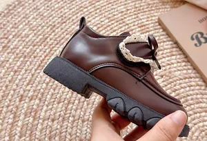 Nahaufnahme von braunen Mädchen-Lederschuhen mit Spitzenbesatz und einer Schleife