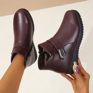 Primer plano de botines granates para mujer con cremallera lateral y hebilla de pedrería