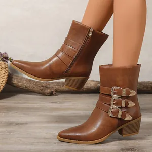 Détail de bottines Chelsea marron style western avec boucles ornées et talon bloc.