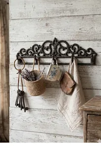Vintage gietijzeren wandhaak met sierlijke krullen op een rustieke houten muur