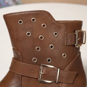 Gros plan d'une botte Chelsea western en cuir marron avec œillets métalliques et boucles