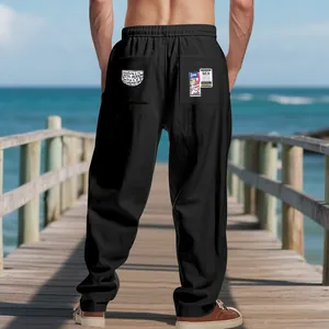 Men's loose black linen beach trousers shown from behind on a scenic wooden pier