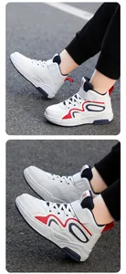 Dettaglio laterale di sneakers bianche da ragazzo con inserti rossi e blu e suola spessa