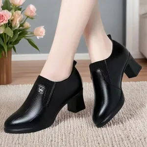 Close-up of black chunky heel loafers with textured patterns and metallic buckle