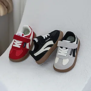 Detailed view of children's German trainer sneakers in red, black, and grey finish