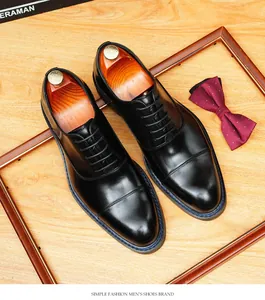 Gros plan de chaussures Oxford en cuir noir avec coutures bleues et embauchoirs en bois.
