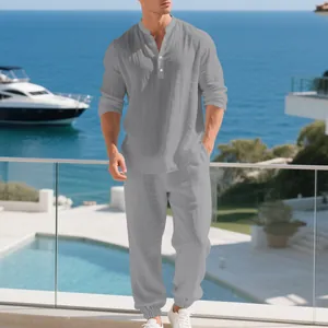 Full view of men's grey linen long-sleeved Henley shirt and pants set on a model outdoors