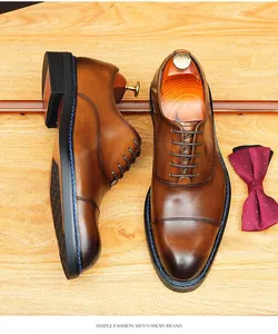 Détail de chaussures Richelieu en cuir marron brossé sur fond de bois.