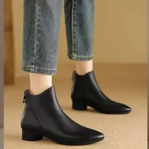 Bottines élégantes en cuir noir à bout pointu et talon moyen épais sur les pieds