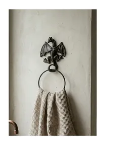 Detailed macro shot of a vintage cast iron dragon towel ring on a rustic textured wall