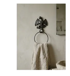 Close-up of vintage cast iron dragon towel ring with linen towel on a textured wall.