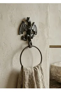 Detail view of a cast iron dragon towel ring holder mounted on a textured wall with towel