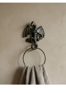 Detailed view of vintage cast iron dragon towel ring with rustic textured wall background.