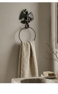 Vintage cast iron dragon towel ring mounted on rustic bathroom wall with textured towel