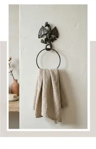 Close-up of vintage cast iron dragon towel ring mounted on a white textured wall.