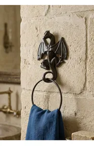 Vintage cast iron dragon towel ring mounted on a rustic stone bathroom wall detail view.
