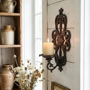 Vintage European style cast iron hollow wall-mounted candle holder with warm lit pillar candle