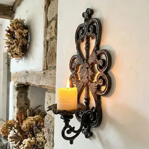 Vintage ornate cast iron wall-mounted candle holder with elegant hollow scrollwork design.