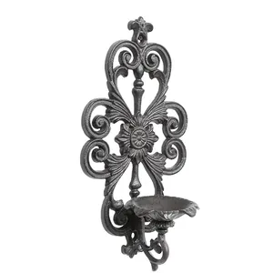 Ornate vintage cast iron wall-mounted candle holder with decorative cutout floral design