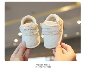 Close-up detail of white princess baby shoes featuring lace trim and quilted leather