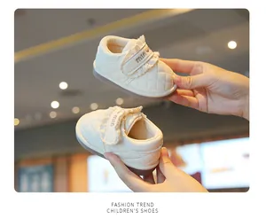 Close-up of cream baby walking shoes with quilted leather and lace trim detail.