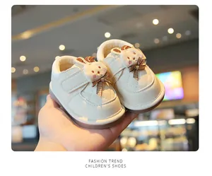 Creamy white baby walking shoes with a cute 3D plush rabbit and plaid bow detail.