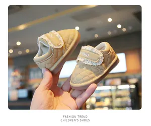 Detail of beige quilted baby girl walking shoes with lace trim and velcro strap.