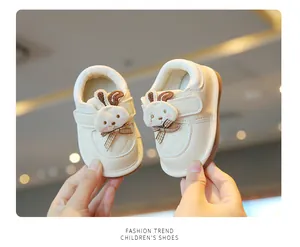Detailed view of cream-colored baby toddler shoes featuring a cute cartoon rabbit design