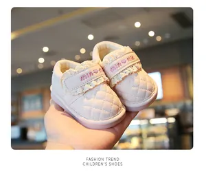 Close-up detail of pink baby princess walking shoes with lace and quilted heart pattern.