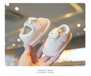 Close-up of pink baby walking shoes with cute cartoon bunny detail held in hand
