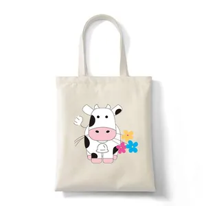 White canvas tote bag featuring a cute cartoon cow and colorful flowers print.