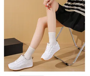 Dettaglio di sneakers bianche in mesh con suola spessa, indossate con calzini bianchi.