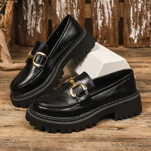 Close-up of black platform loafers with crocodile texture and gold buckle detail