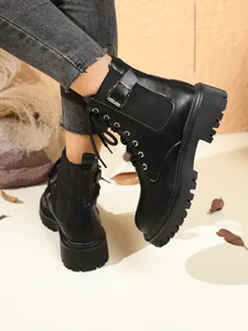 Detailed side view of black platform ankle boots featuring a metal buckle and chunky lug sole.