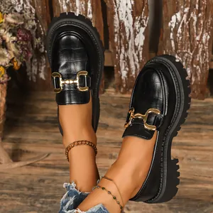 Close-up detail of stylish black crocodile-embossed platform loafers with gold buckle.