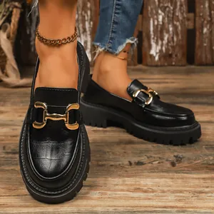 Macro detail of black croc-embossed platform loafers featuring a gold horsebit buckle