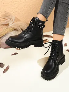 Close-up of black British style platform boots with buckle and lace-up detail.